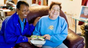A woman bringing a meal to another woman at home