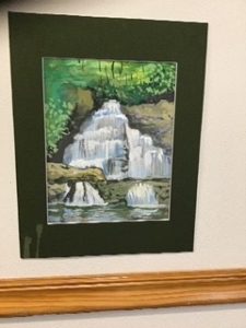 A painting of a waterfall hung on a wall