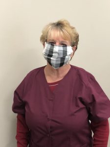 A woman wearing a plaid protective face mask