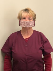 A woman wearing a burgundy floral protective face mask