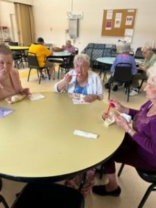 older women seated at a table eating banana splits