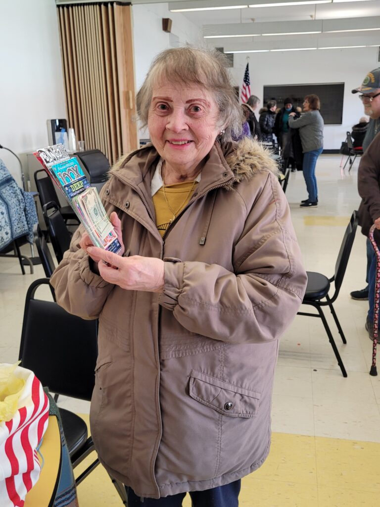 Older adult woman smiling and holding a bingo prize at a Bingo Bash event at Turtle Creek Senior Center.