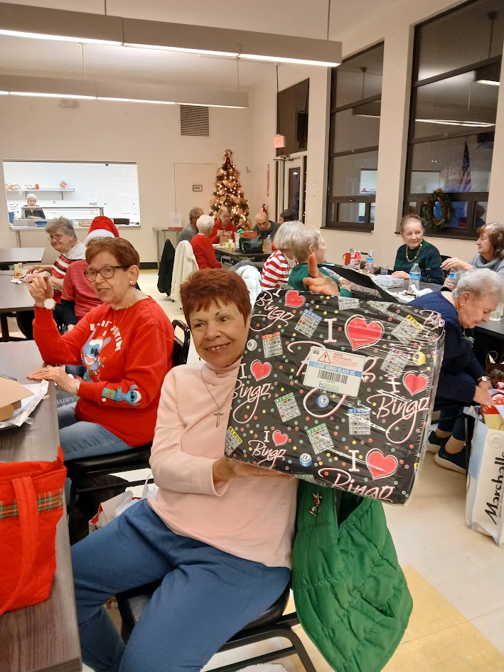 A woman holds up a large wrapped gift
